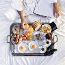 Bandeja de café sobre cama branca.
